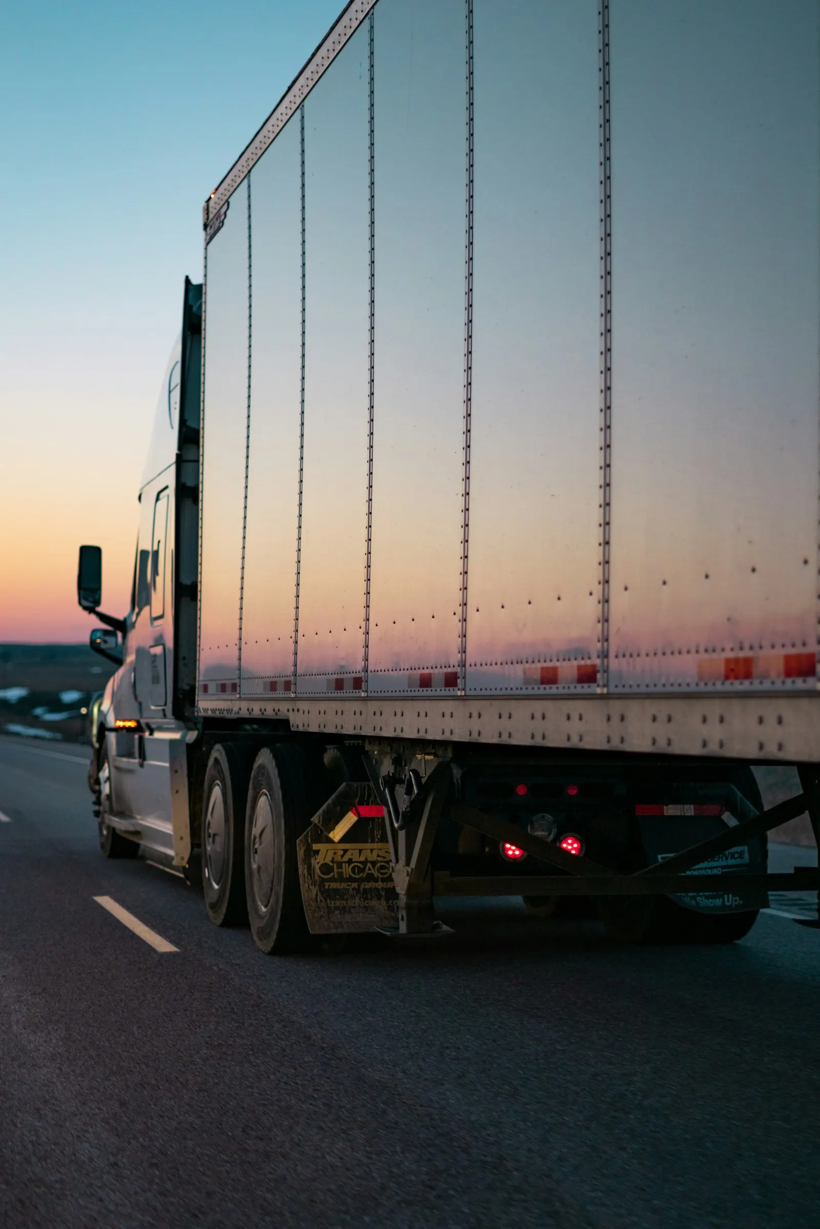 Camión de carga en carretera al atardecer; fotografía de referencia de entrega.
